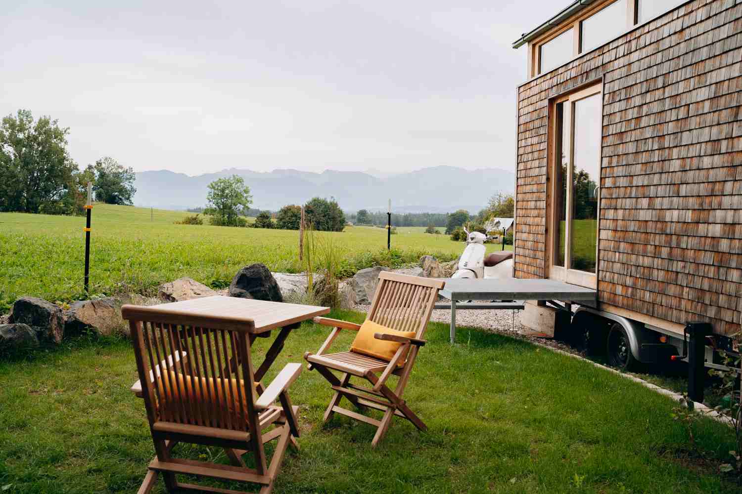 Sitzbereich im Garten eines Tiny Houses mit Blick auf Wiesen und Berge.